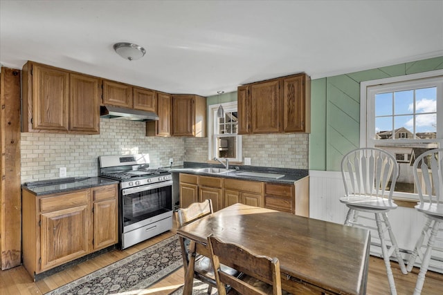 kitchen featuring sink, backsplash, stainless steel range with gas stovetop, and light wood-type flooring