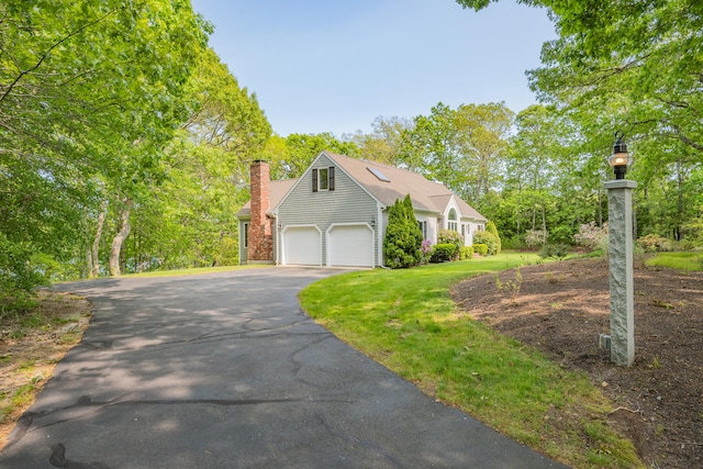 23 Walkerwoods Dr, Harwich, MA 02645 - view of front facade with asphalt driveway, a front yard, a chimney, and view of wooded area