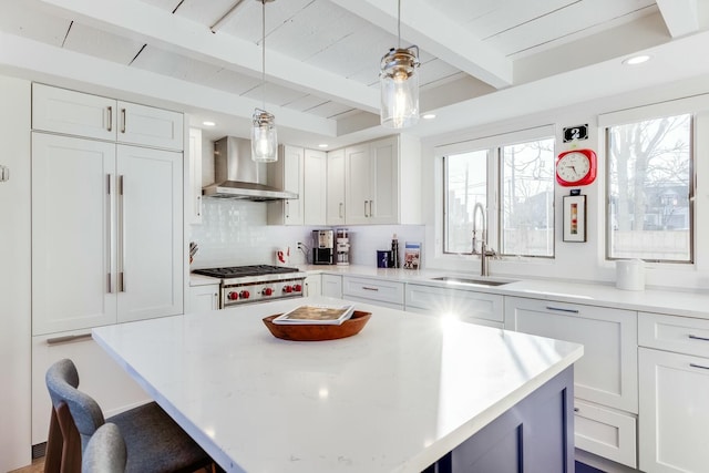 kitchen with wall chimney exhaust hood, a kitchen bar, sink, white cabinetry, and a kitchen island