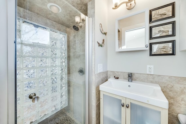 bathroom with walk in shower, vanity, and tile walls