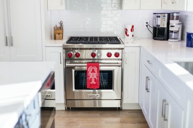 kitchen featuring premium stove, white cabinets, and light wood-type flooring