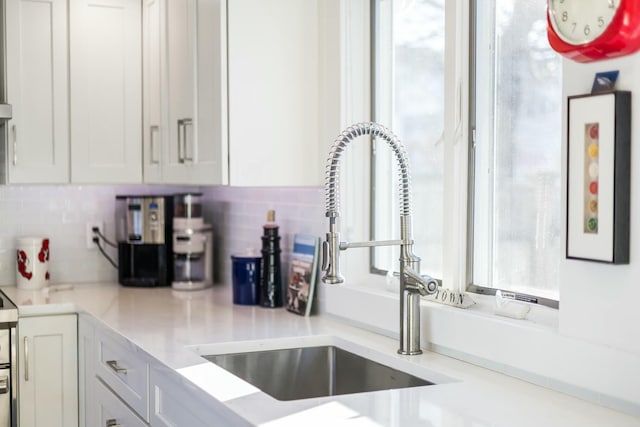 kitchen featuring tasteful backsplash, sink, and white cabinets