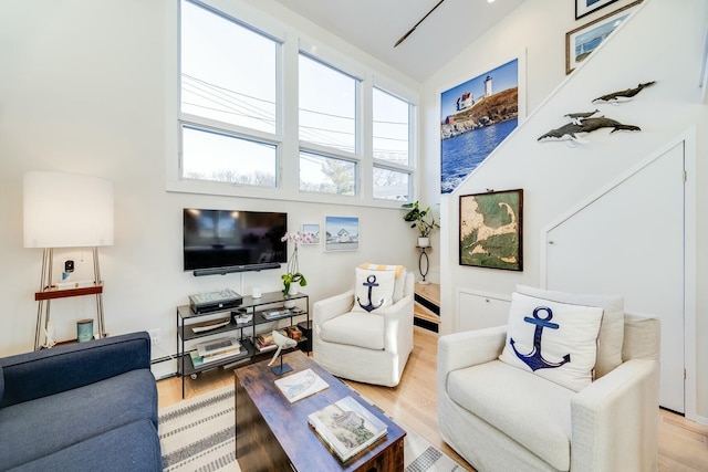 living room with a high ceiling, light wood-type flooring, and baseboard heating