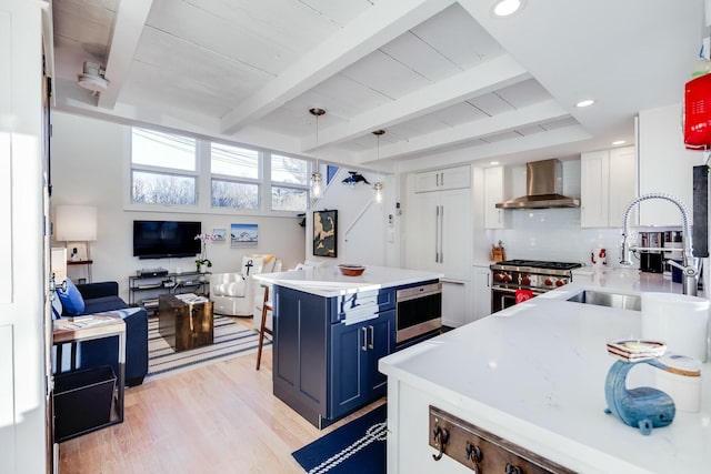 kitchen featuring wall chimney range hood, high end stainless steel range oven, white cabinetry, hanging light fixtures, and blue cabinets