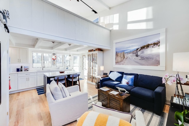 living room featuring sink, light hardwood / wood-style floors, french doors, and beamed ceiling