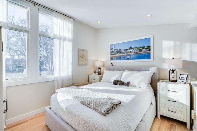 bedroom featuring multiple windows, light hardwood / wood-style floors, and lofted ceiling