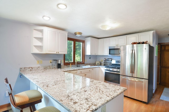 59 Whitecaps Dr, East Falmouth, MA 02536 - kitchen with stainless steel appliances, a peninsula, light wood-style floors, and white cabinetry