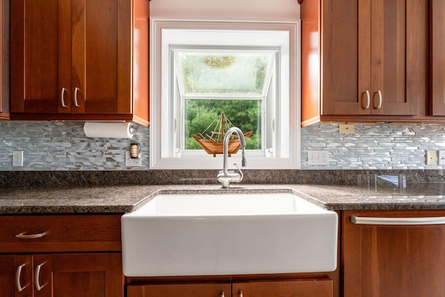 kitchen featuring tasteful backsplash, dark countertops, a sink, and brown cabinets