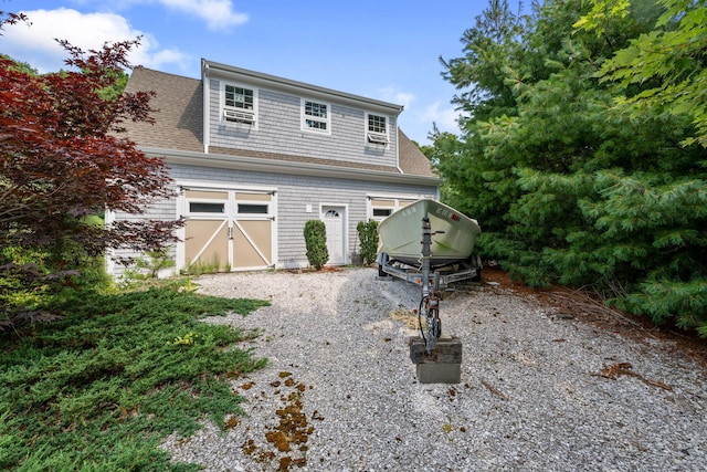 view of front facade with driveway and a shingled roof