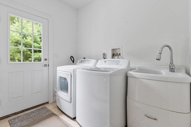 laundry area with laundry area, a sink, washer and clothes dryer, and light tile patterned floors