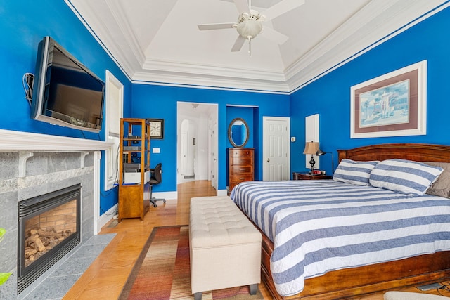 bedroom featuring a fireplace, lofted ceiling, ornamental molding, ceiling fan, and wood finished floors