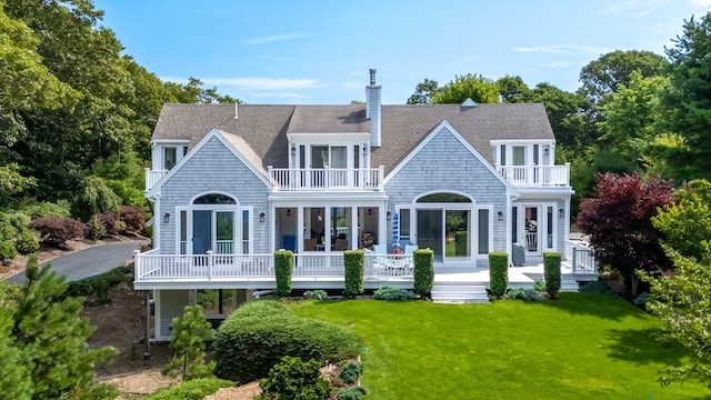 rear view of house with a shingled roof, a lawn, a chimney, and a balcony