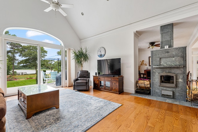 living area with ornamental molding, a tile fireplace, ceiling fan, and wood finished floors