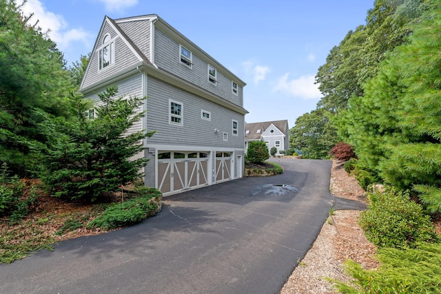 view of side of home featuring a garage and aphalt driveway