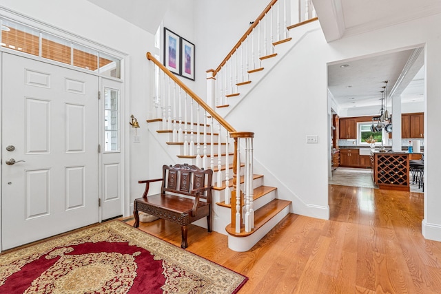 foyer with light wood-style flooring, stairway, and baseboards