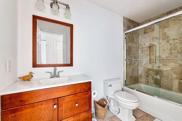 bathroom featuring toilet, tile patterned flooring, combined bath / shower with glass door, and vanity