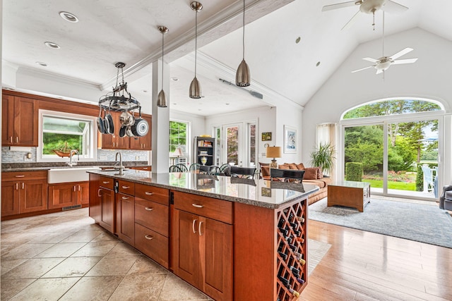 kitchen featuring a healthy amount of sunlight, a center island with sink, open floor plan, and a sink