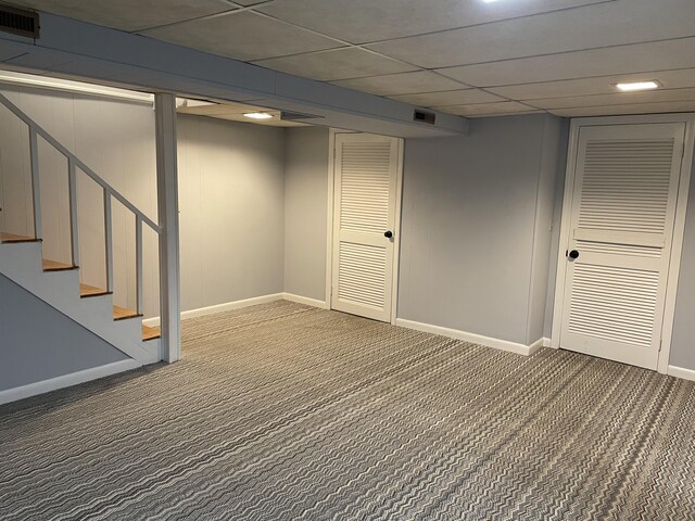 basement with a paneled ceiling and carpet floors