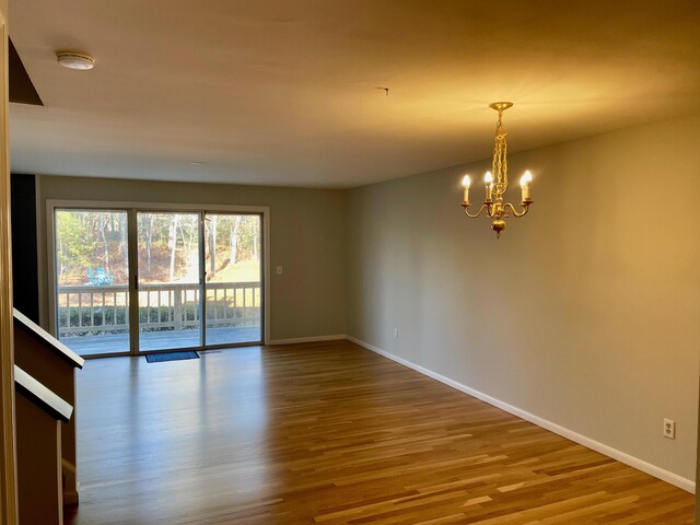 spare room featuring wood-type flooring and a chandelier