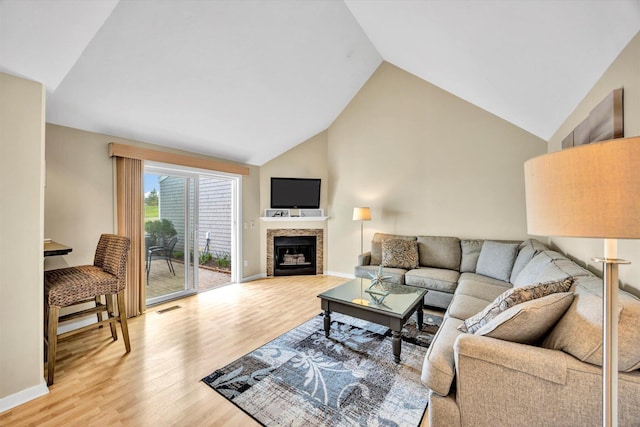 living area with light wood finished floors, a fireplace, high vaulted ceiling, baseboards, and visible vents