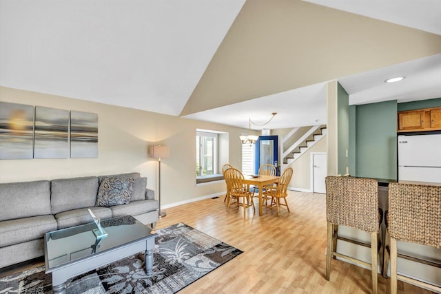 living room featuring an inviting chandelier, stairs, baseboards, high vaulted ceiling, and light wood finished floors