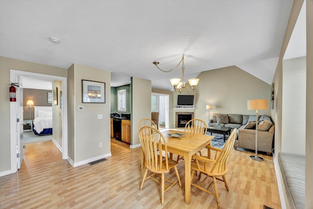dining space with visible vents, a fireplace, baseboards, light wood finished floors, and a chandelier