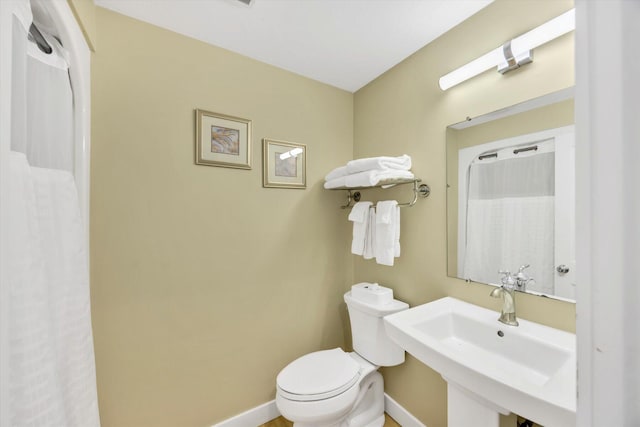 bathroom with a sink, baseboards, and toilet