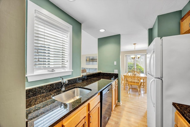 kitchen with freestanding refrigerator, dishwashing machine, a chandelier, a sink, and light wood finished floors