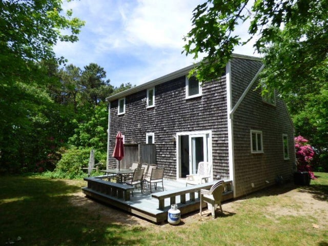 rear view of house with a wooden deck and a lawn