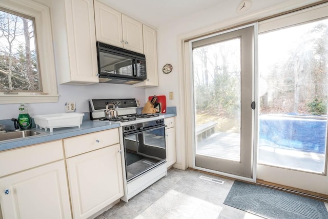 kitchen with sink, white cabinetry, and white range with gas stovetop