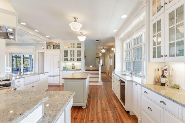 kitchen with white cabinets, a center island, a sink, and light wood-style flooring