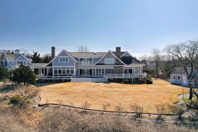 rear view of house featuring a chimney, an outdoor structure, a yard, and a deck