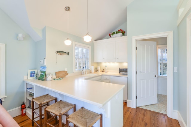 20 Boat Meadow Way, Eastham, MA 02642 - kitchen featuring a kitchen breakfast bar, a peninsula, light wood-style flooring, white cabinetry, and lofted ceiling