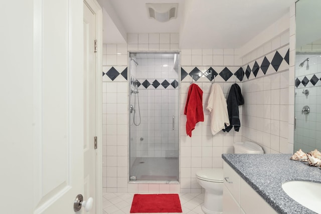 full bathroom featuring a stall shower, vanity, tile walls, toilet, and tile patterned flooring