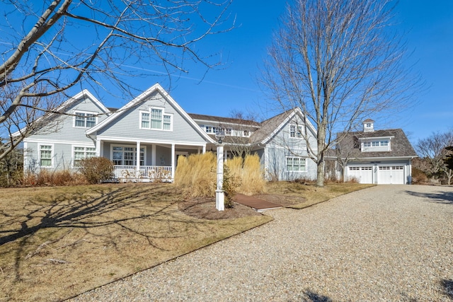 view of front of home featuring a garage, driveway, a porch, and an outdoor structure