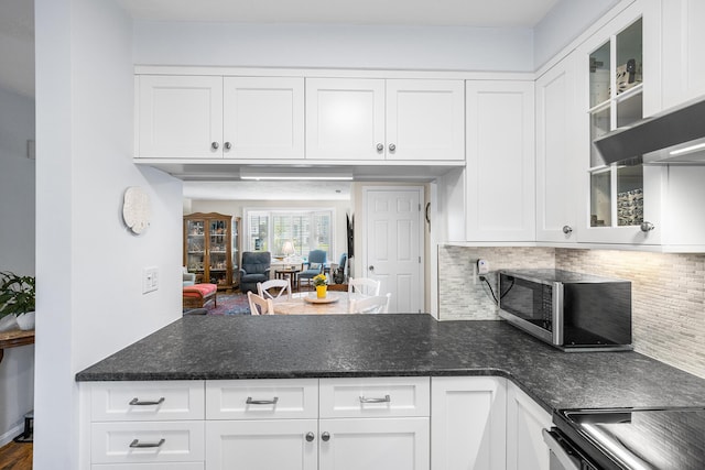 441 Buck Island Rd Unit B1, West Yarmouth, MA 02673 - kitchen with stainless steel microwave, a peninsula, tasteful backsplash, white cabinetry, and glass insert cabinets