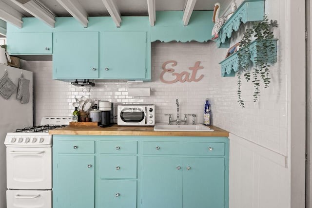 kitchen with a sink, blue cabinetry, white range with gas stovetop, backsplash, and butcher block counters