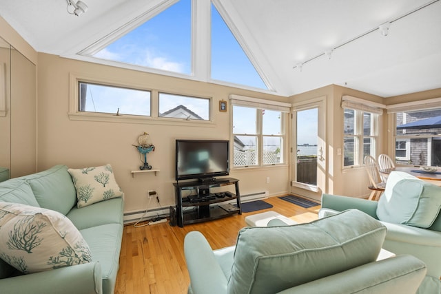 living room with light hardwood / wood-style floors, a baseboard radiator, and a wealth of natural light