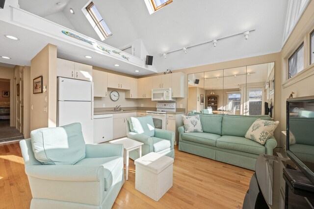 living room with sink, a skylight, high vaulted ceiling, and light hardwood / wood-style floors