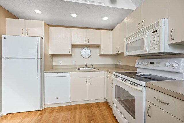 kitchen featuring white cabinetry, sink, white appliances, and light hardwood / wood-style flooring