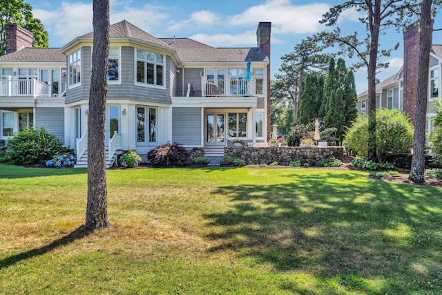 back of property with a balcony and a lawn