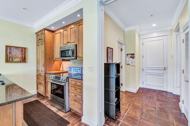 kitchen featuring stainless steel appliances, dark stone counters, ornamental molding, and tasteful backsplash