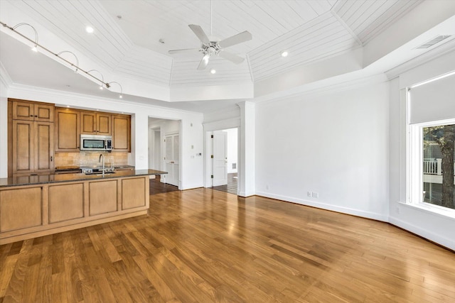 kitchen featuring sink, hardwood / wood-style flooring, ceiling fan, backsplash, and ornamental molding