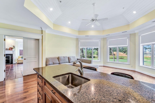 kitchen featuring wood ceiling, sink, ornamental molding, dark stone counters, and a tray ceiling