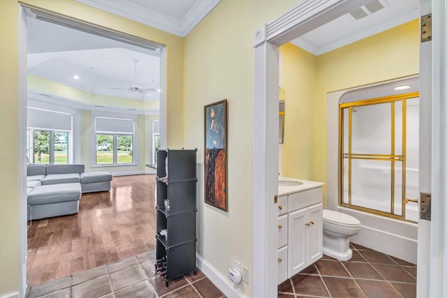 full bathroom with ceiling fan, combined bath / shower with glass door, toilet, vanity, and ornamental molding