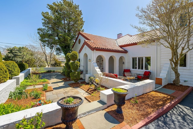 rear view of property featuring stucco siding, a tile roof, a chimney, and a patio area