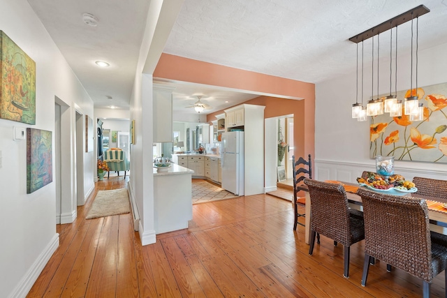 dining area featuring light wood finished floors, a wealth of natural light, baseboards, and a ceiling fan
