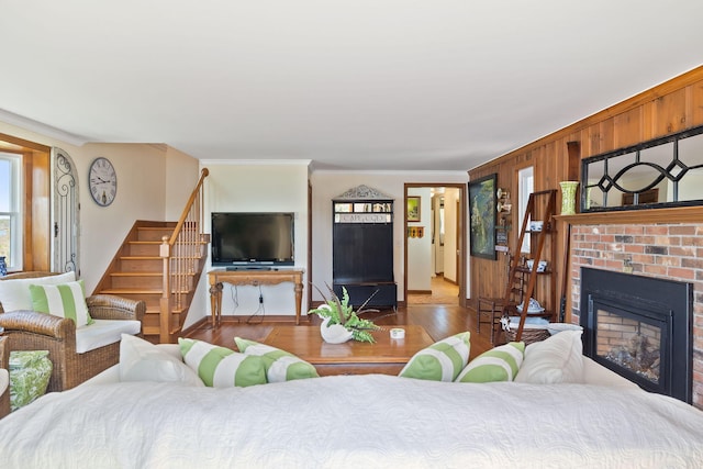 living area featuring baseboards, crown molding, wood finished floors, stairway, and a fireplace