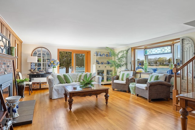 living area featuring a wealth of natural light, ornamental molding, light wood finished floors, and a fireplace with flush hearth
