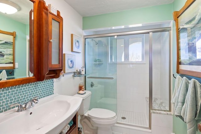 full bath featuring a sink, toilet, tasteful backsplash, and a shower stall